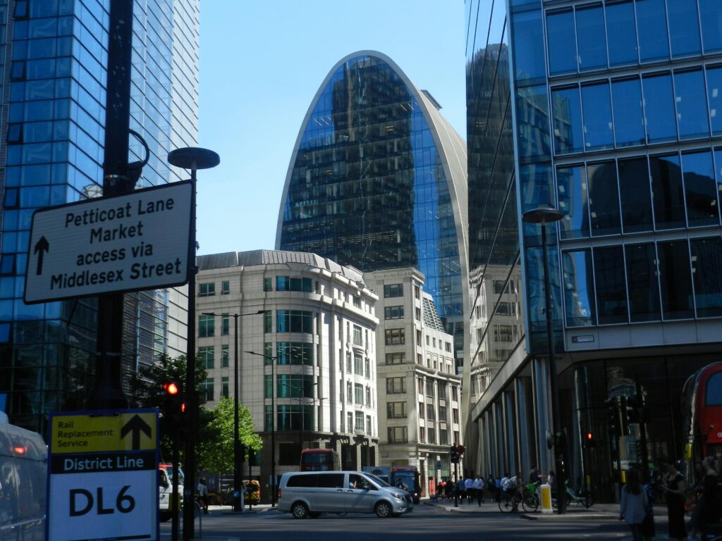 People Walking on Sidewalk Between Modern Architectural Buildings with Glass Panel Windows